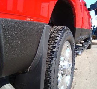 Back of red pickup showing black spray by back wheel