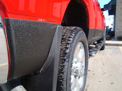 Back of red pickup showing black spray by back wheel